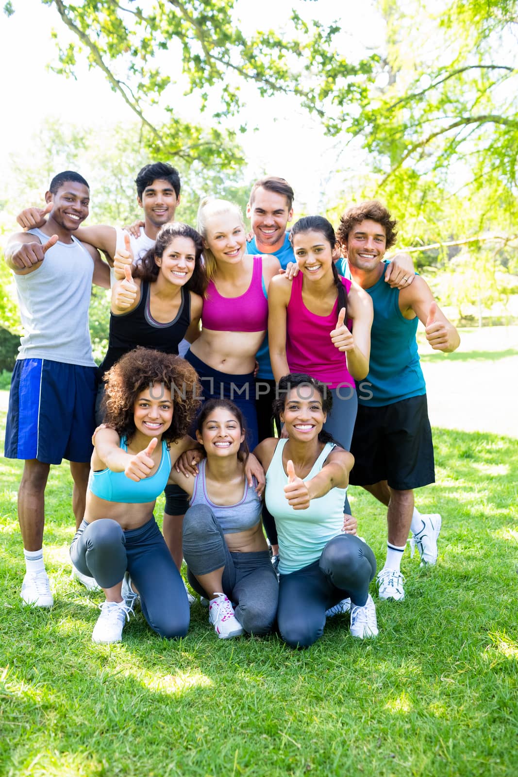 Group portrait of friends in sportswear showing thumbs up at the park