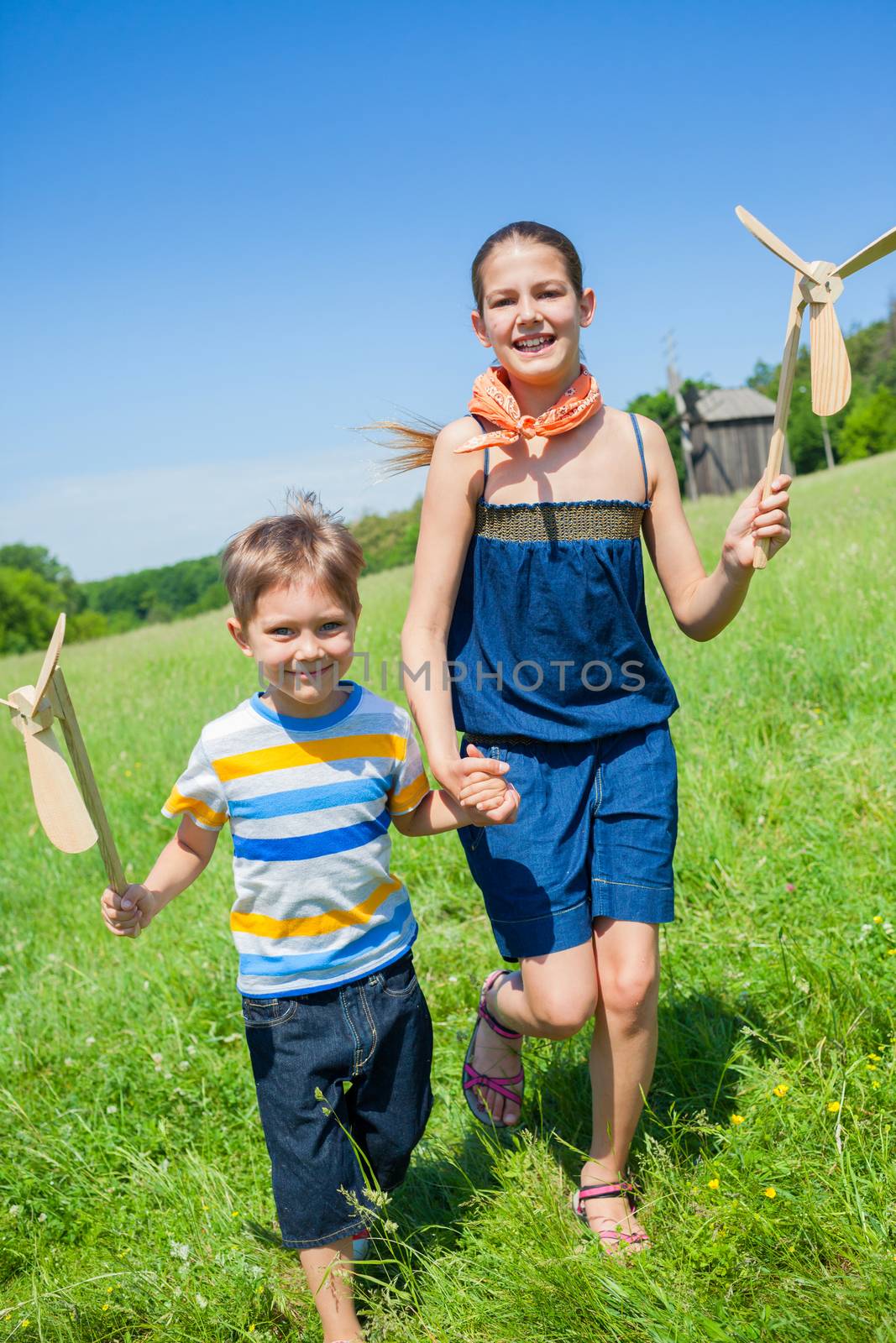 Kids in summer day holds windmill by maxoliki