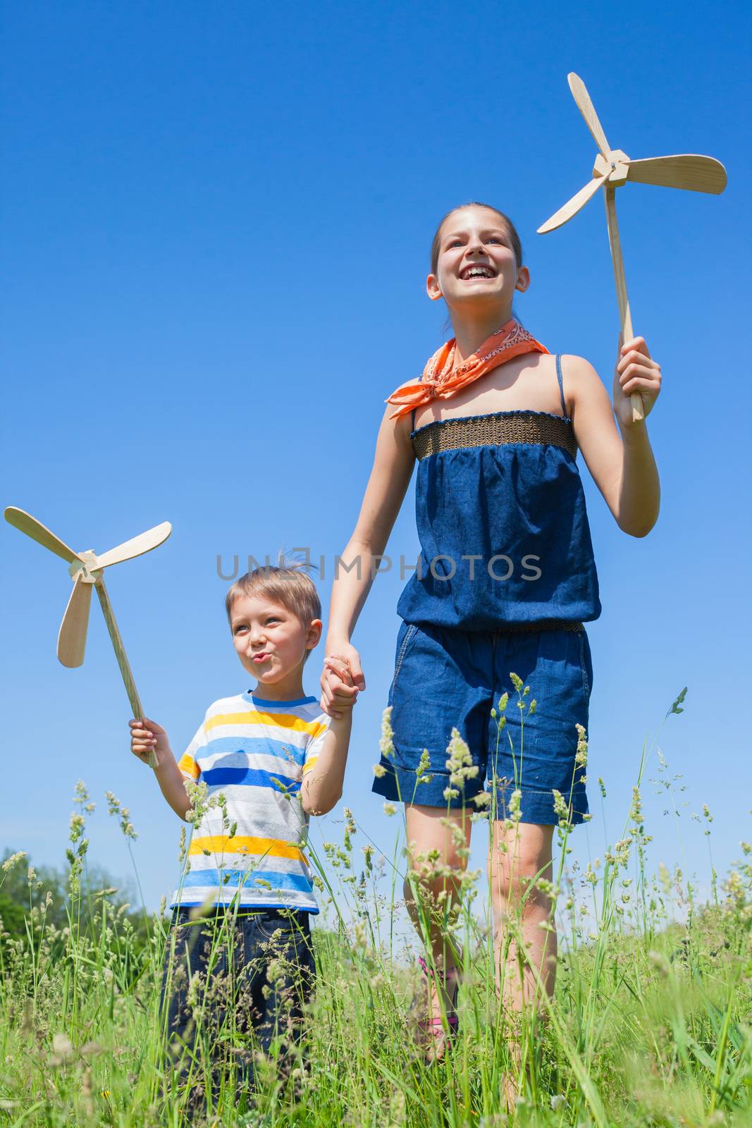 Kids in summer day holds windmill by maxoliki