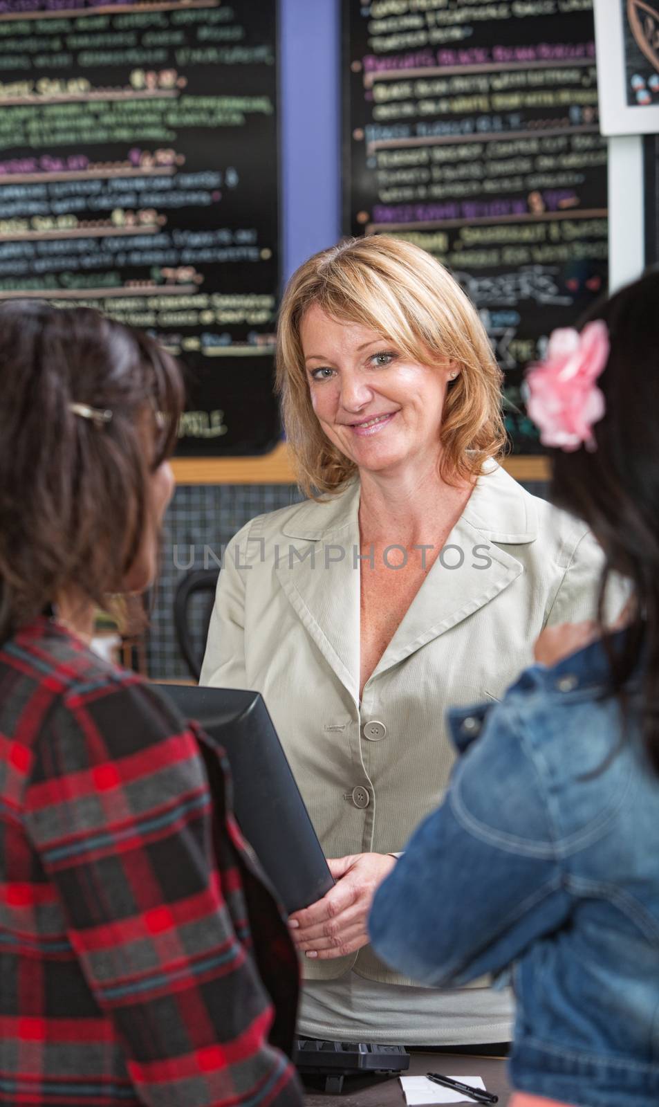 Cheerful restaurant owner at counter with customers