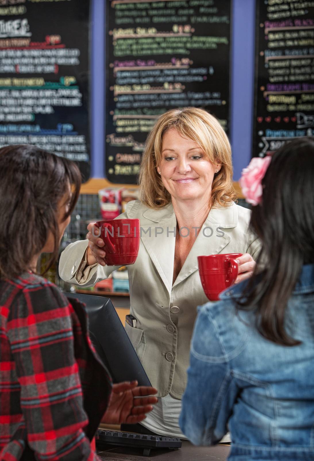 Smiling cafe owner serving drinks to customers