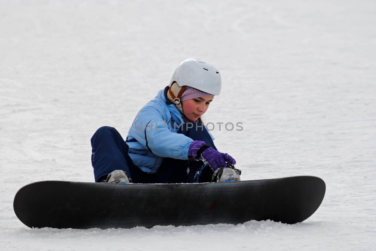 Little girl preparing for the descent of the mountain on a snowboard.