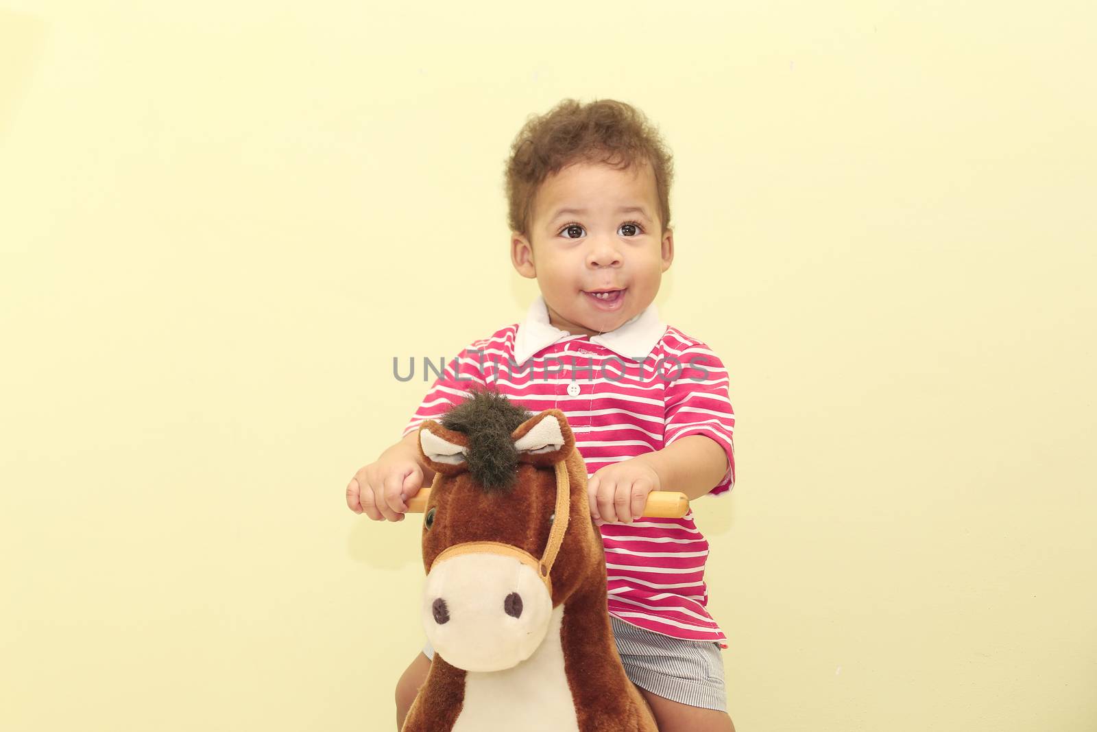 Portrait of an adorable african boy in his horse toy.