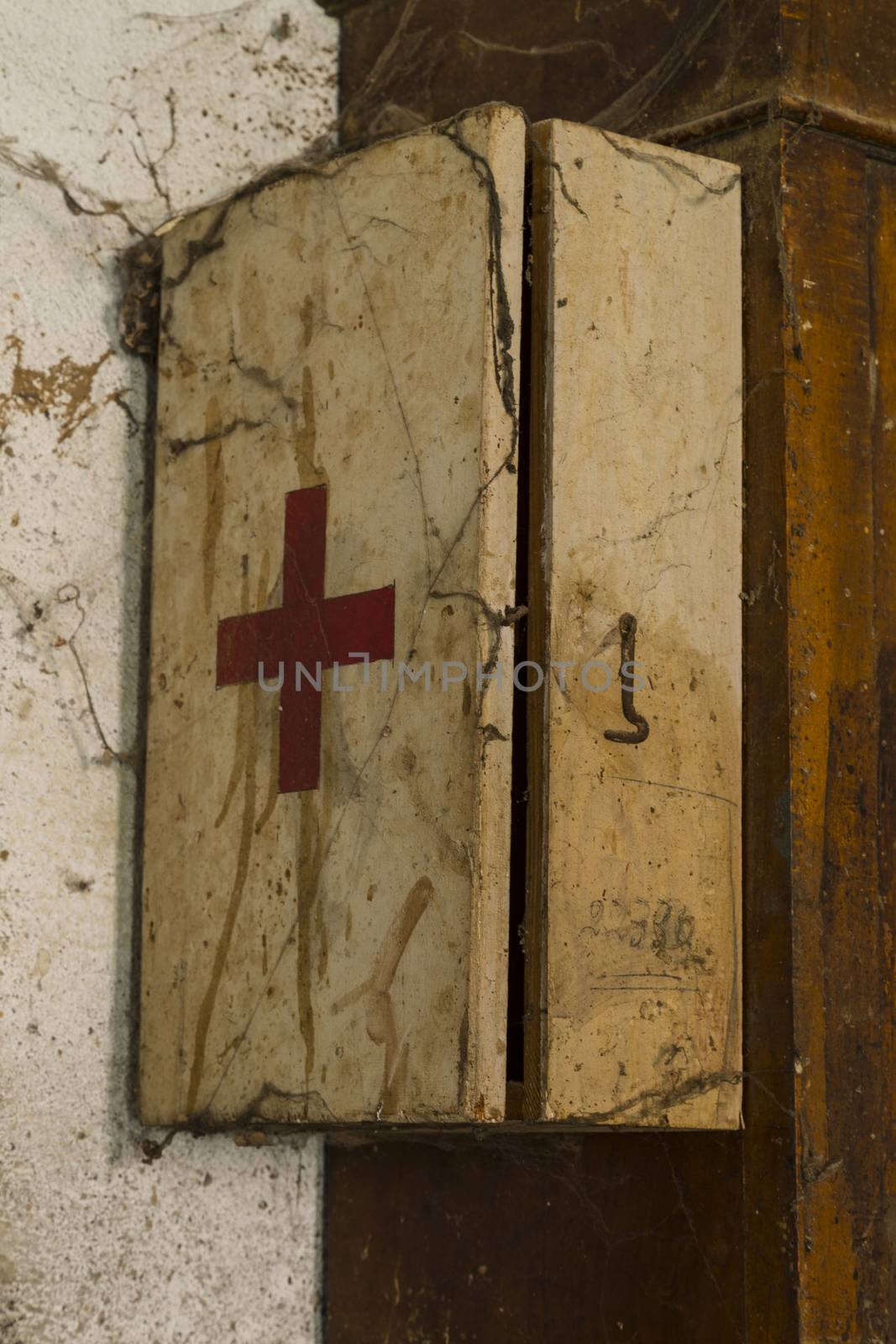 An old first aid kit on a dirty and rusty wall covered by cobwebs