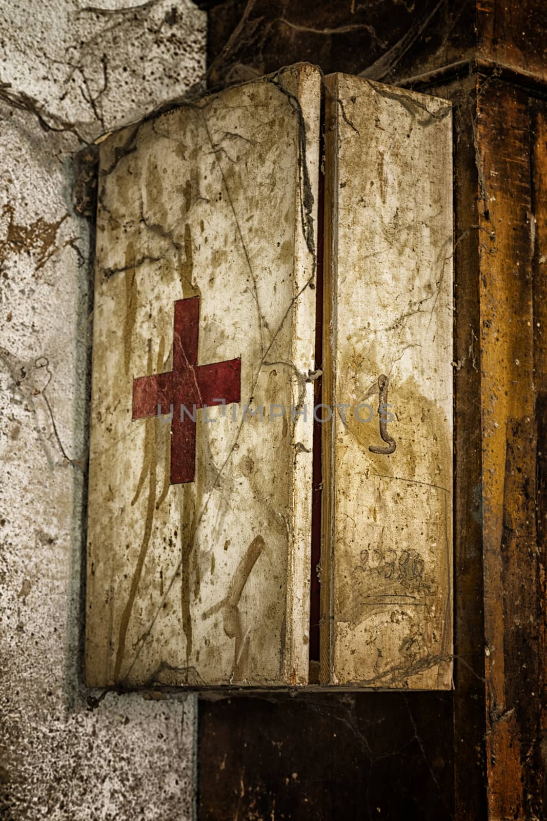 An old first aid kit on a dirty and rusty wall covered by cobwebs