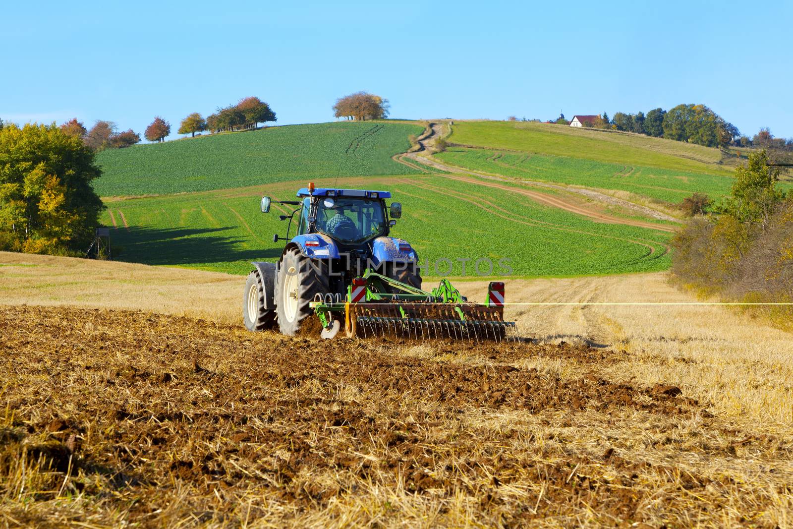 farm tractor on the field working, plowing land by motorolka