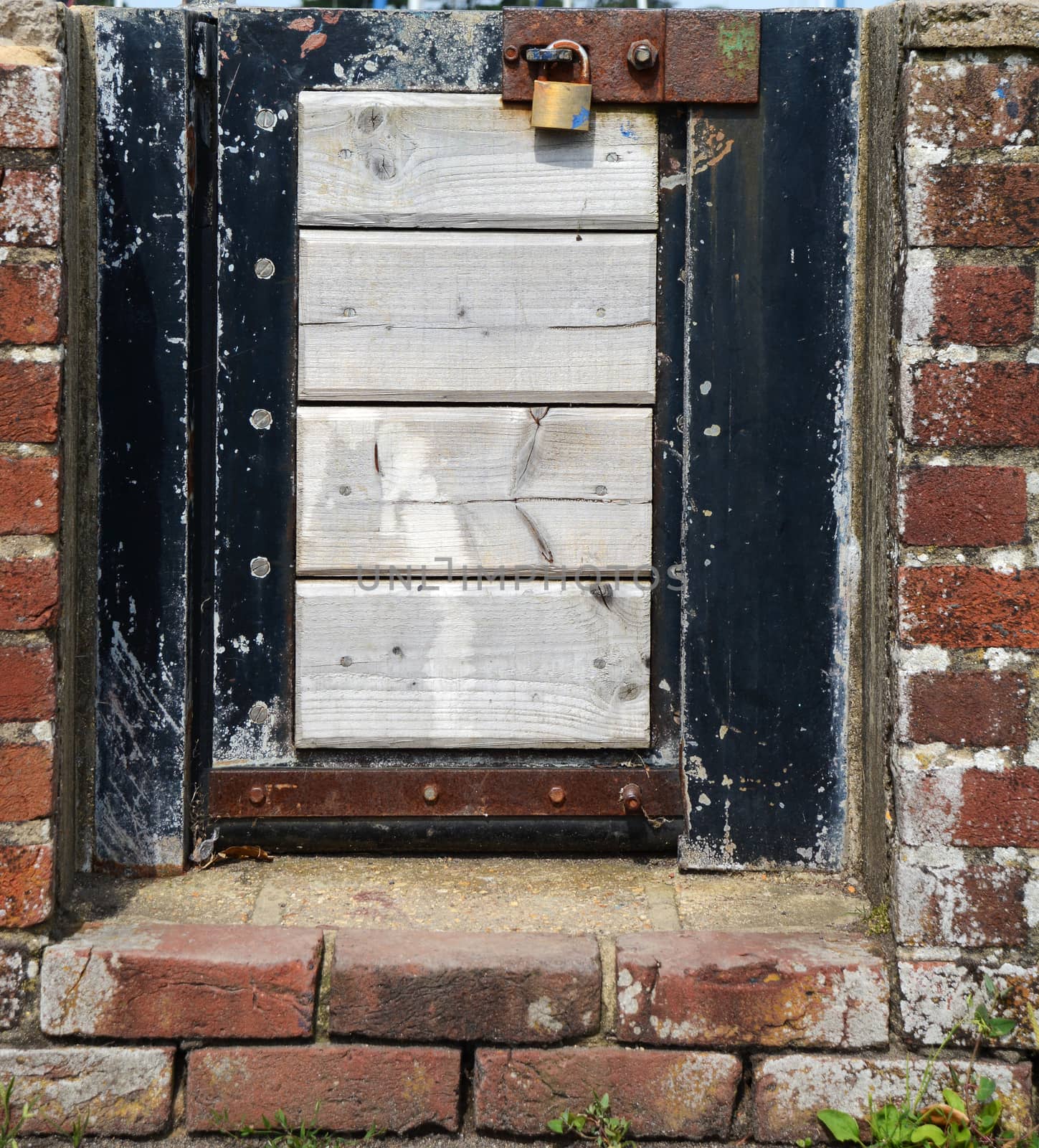 Small wood and metal gate in a brick wall, padlocked shut