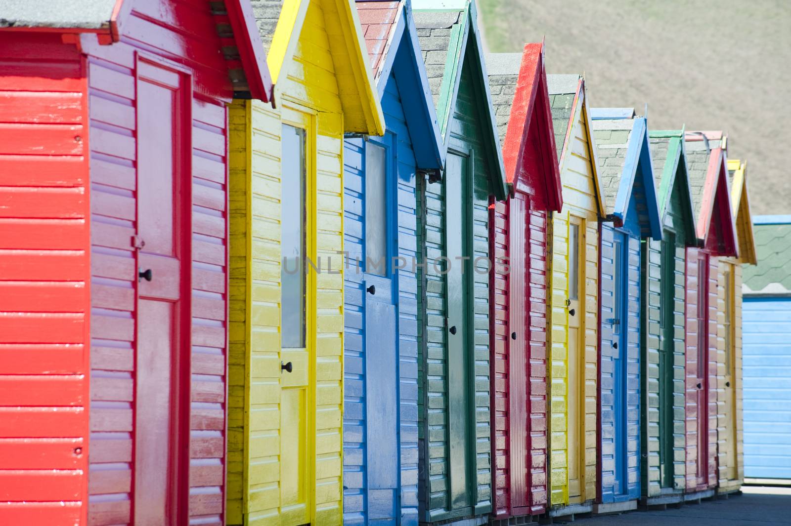 Row of colorful traditional wooden beach huts overlooking the Whitby Sands beach, Whitby, North Yorkshire, close up view receding from the camera