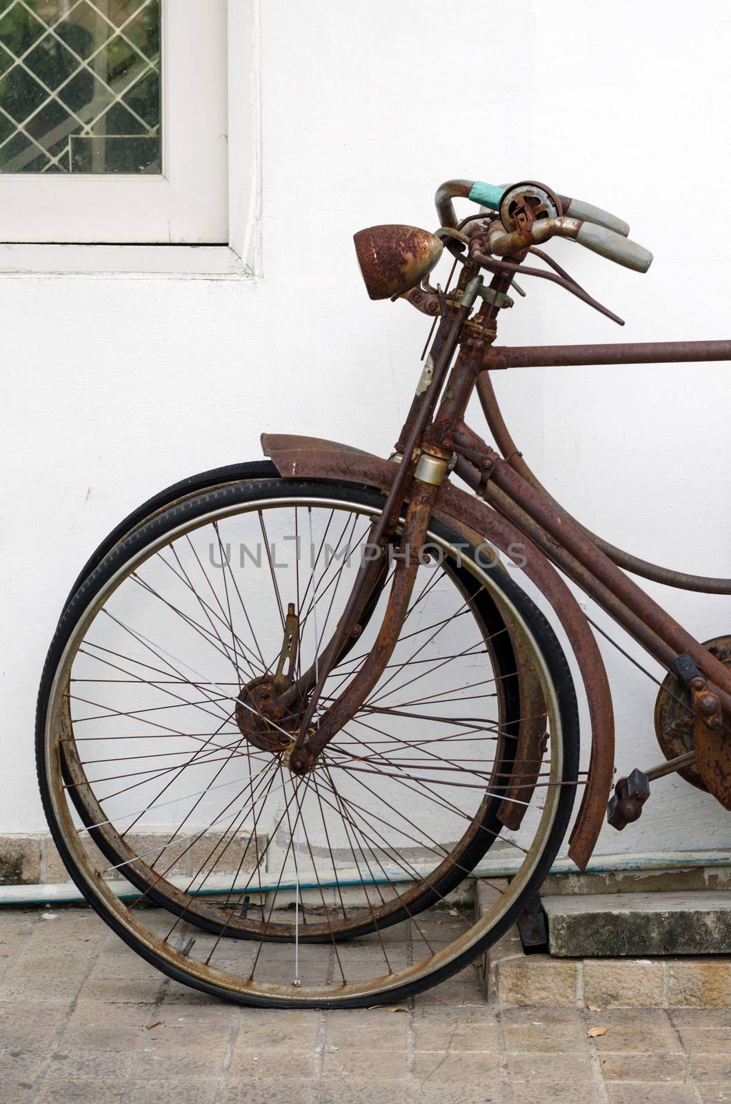 Old rusty vintage bicycle near concrete wall