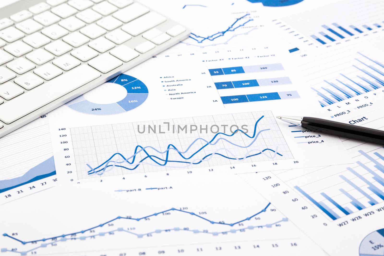 closeup blue graph and chart reports with white keyboard and pen on office table, financial and business concept