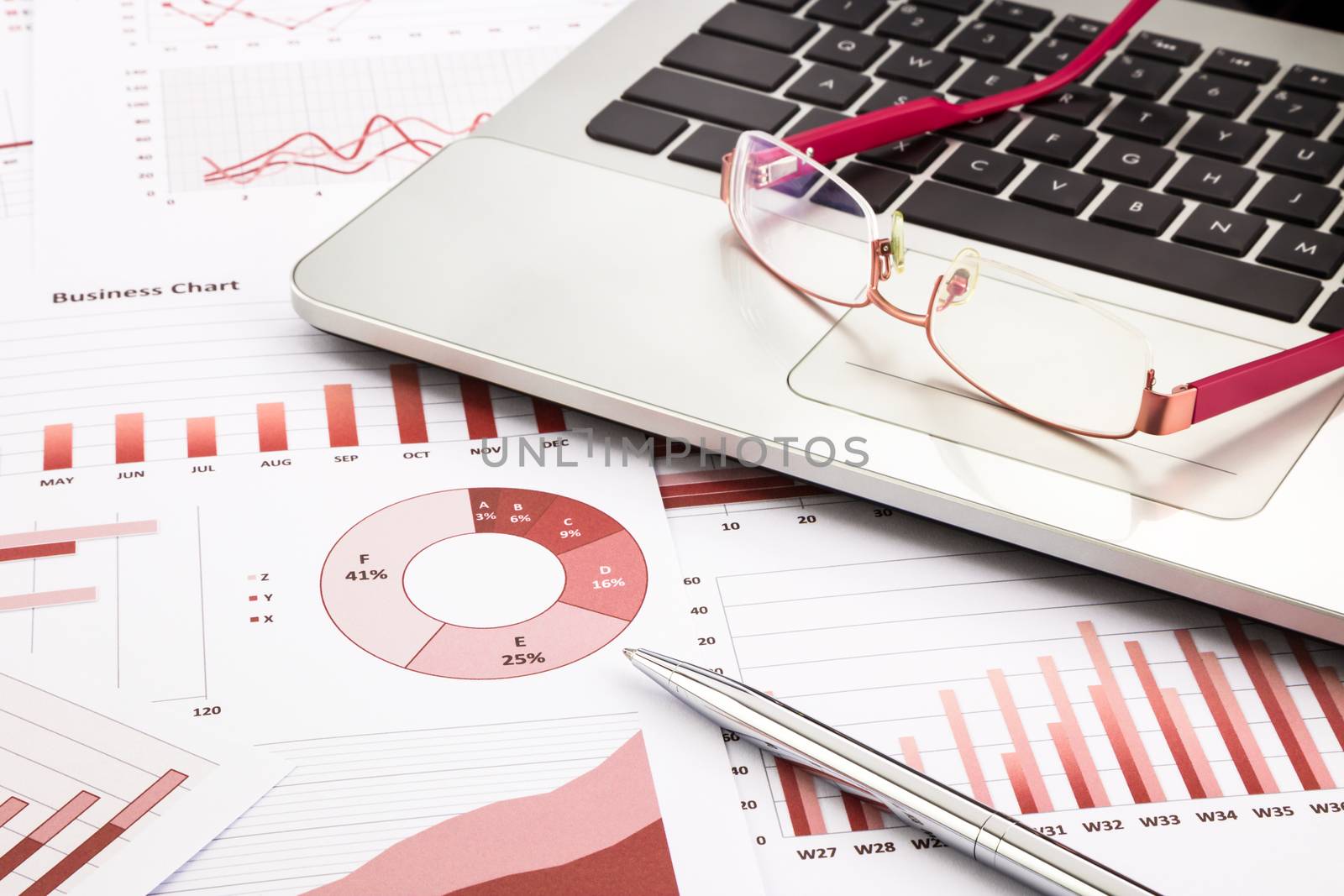 laptop and glasses with red business charts, graphs, research and reports background for management and business concepts