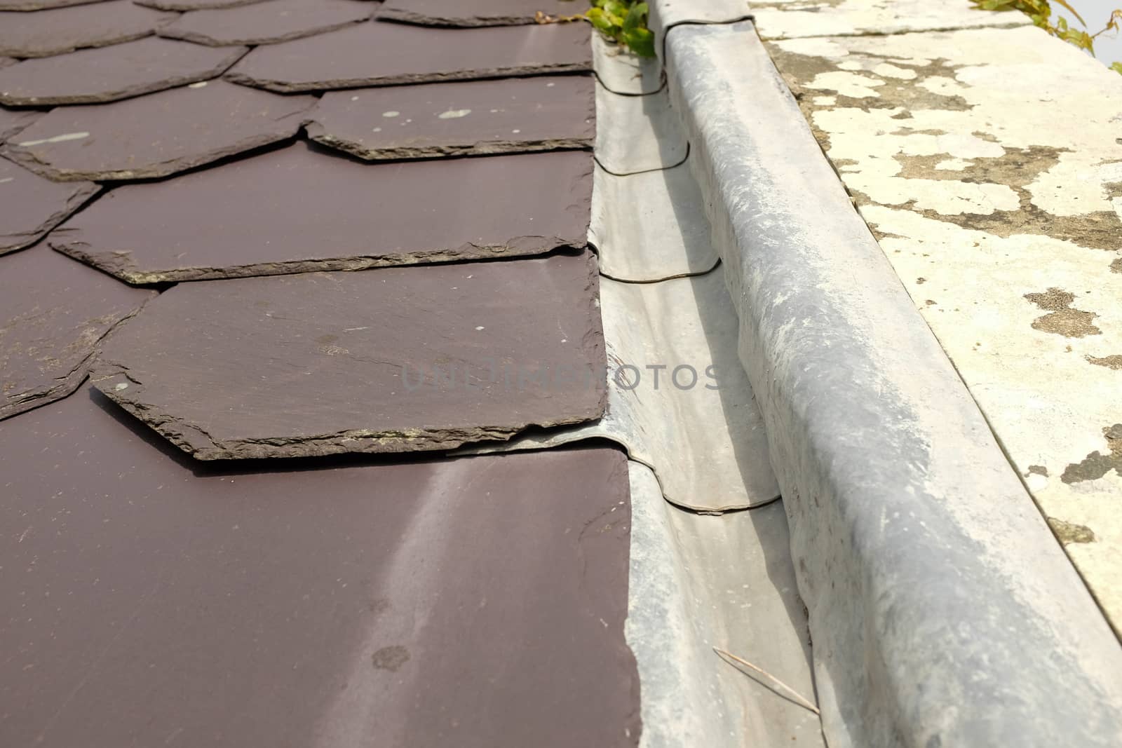 A cut slate roof with a lead valley edge under-lapping the slates.