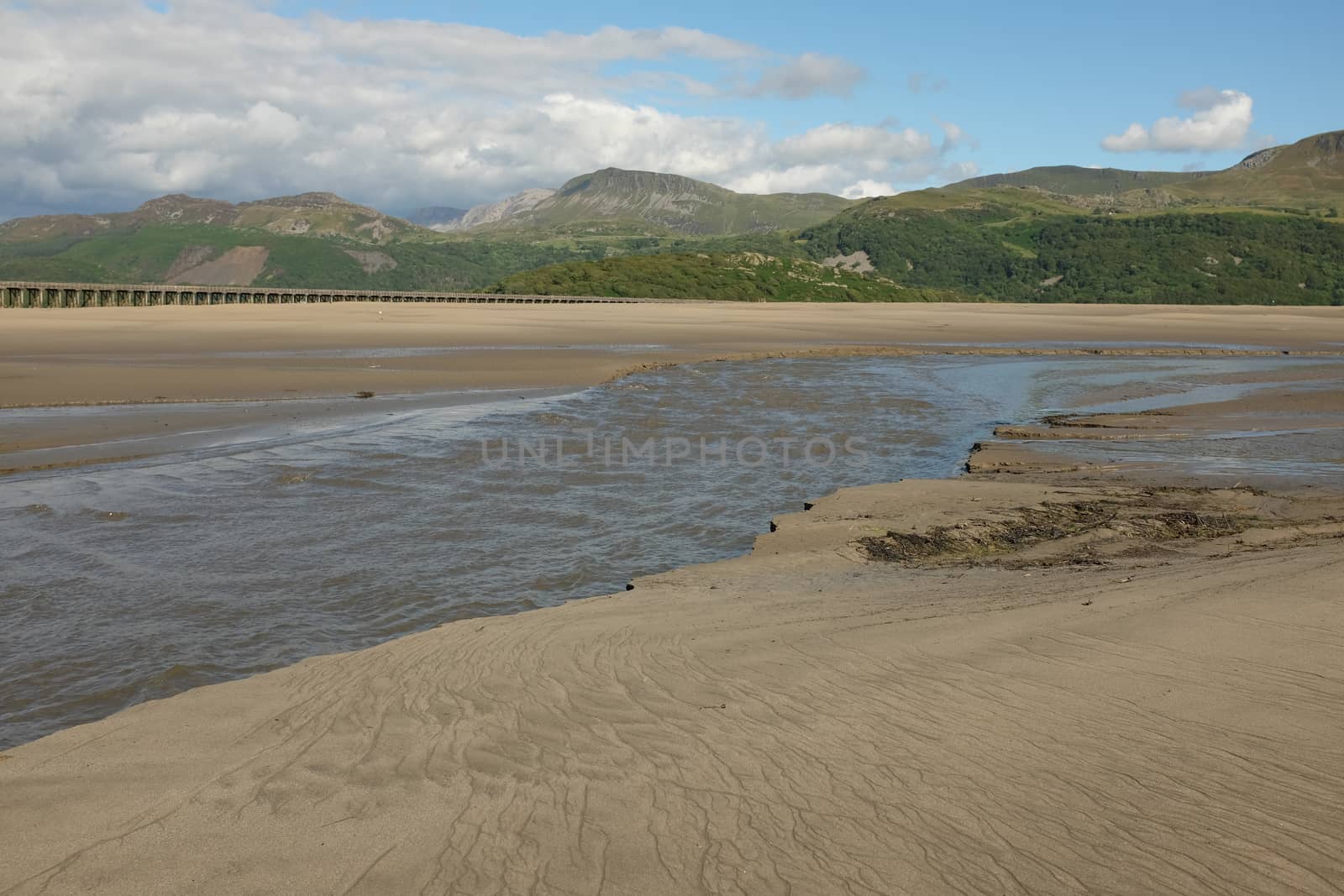 Patterned sand and a river looks out across the Mawddach estuary with the mountain Cadair Idris in the distance, Gwynedd, Wales, UK.