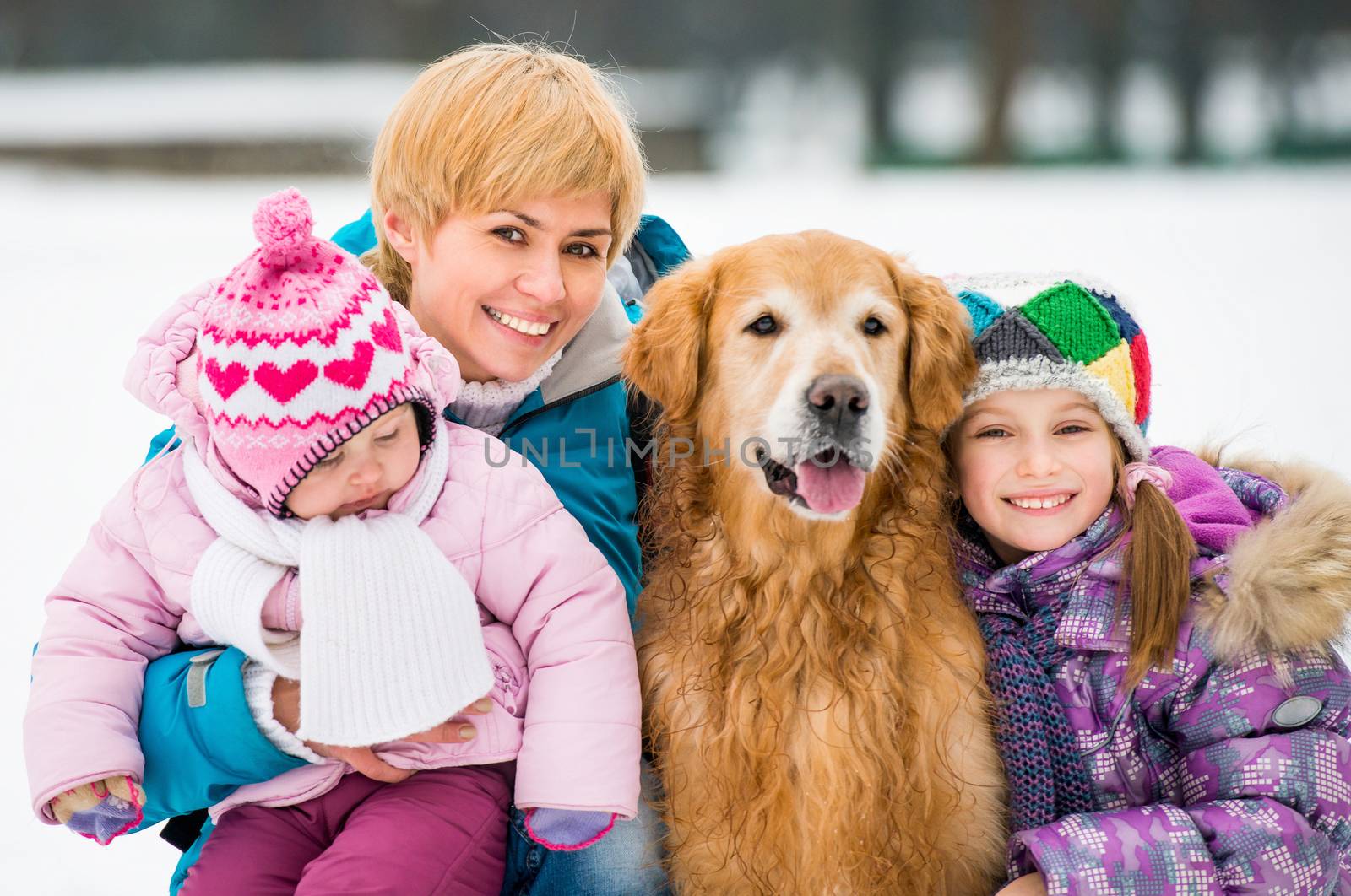 Happy baeutiful family on a winter walk with the dog