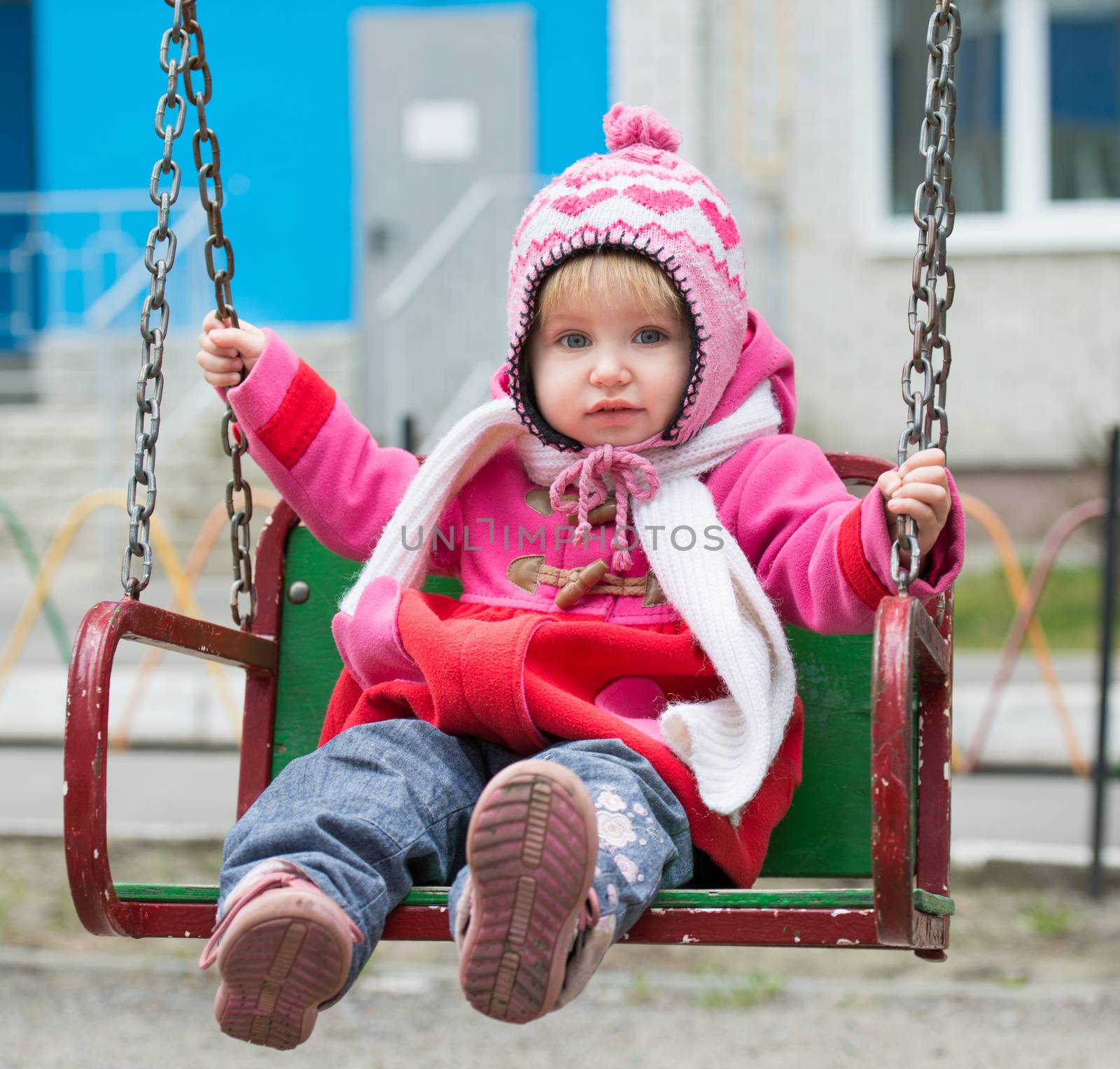 Little girl on the playground ride on a swing