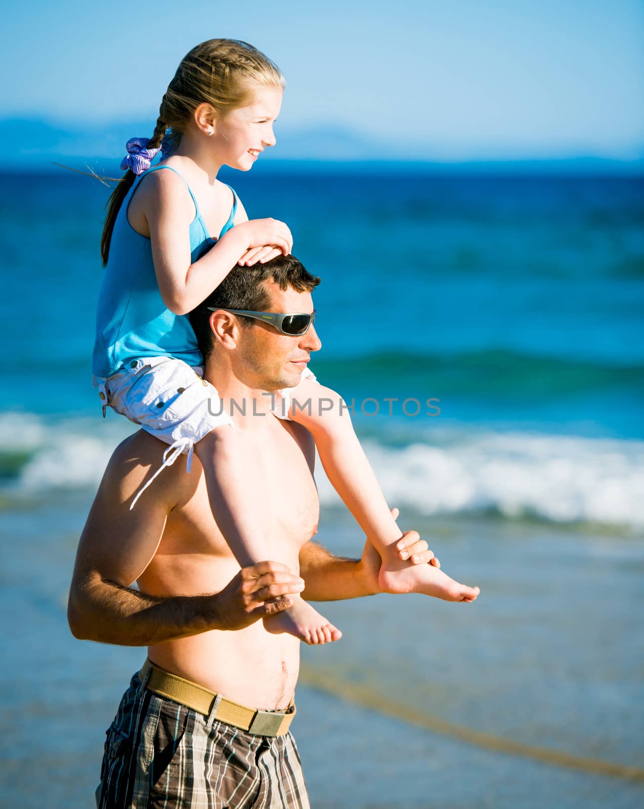 Portrait of happy father and his adorable little daughter on the beach