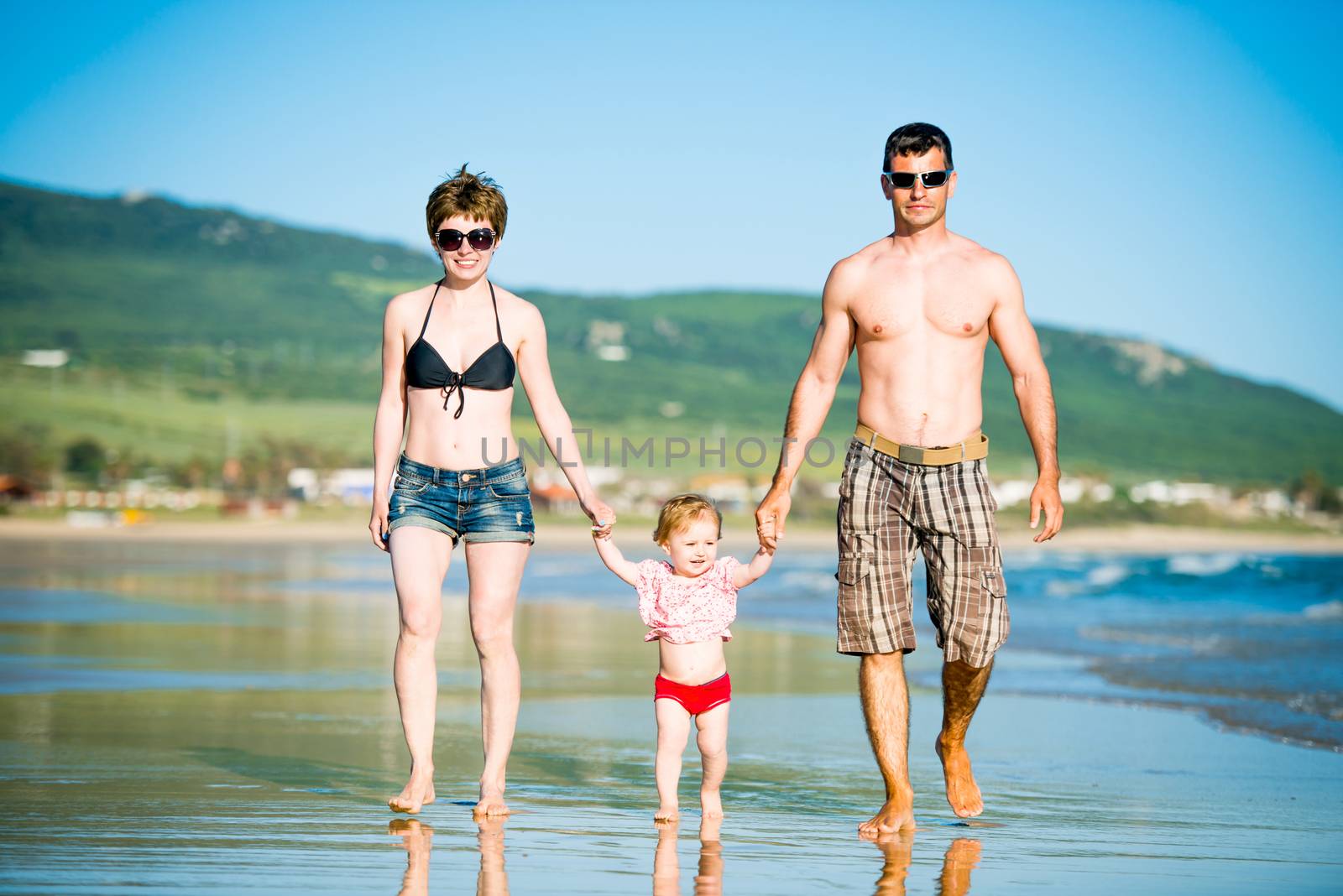 Beautiful family with little daughter playing on the beach