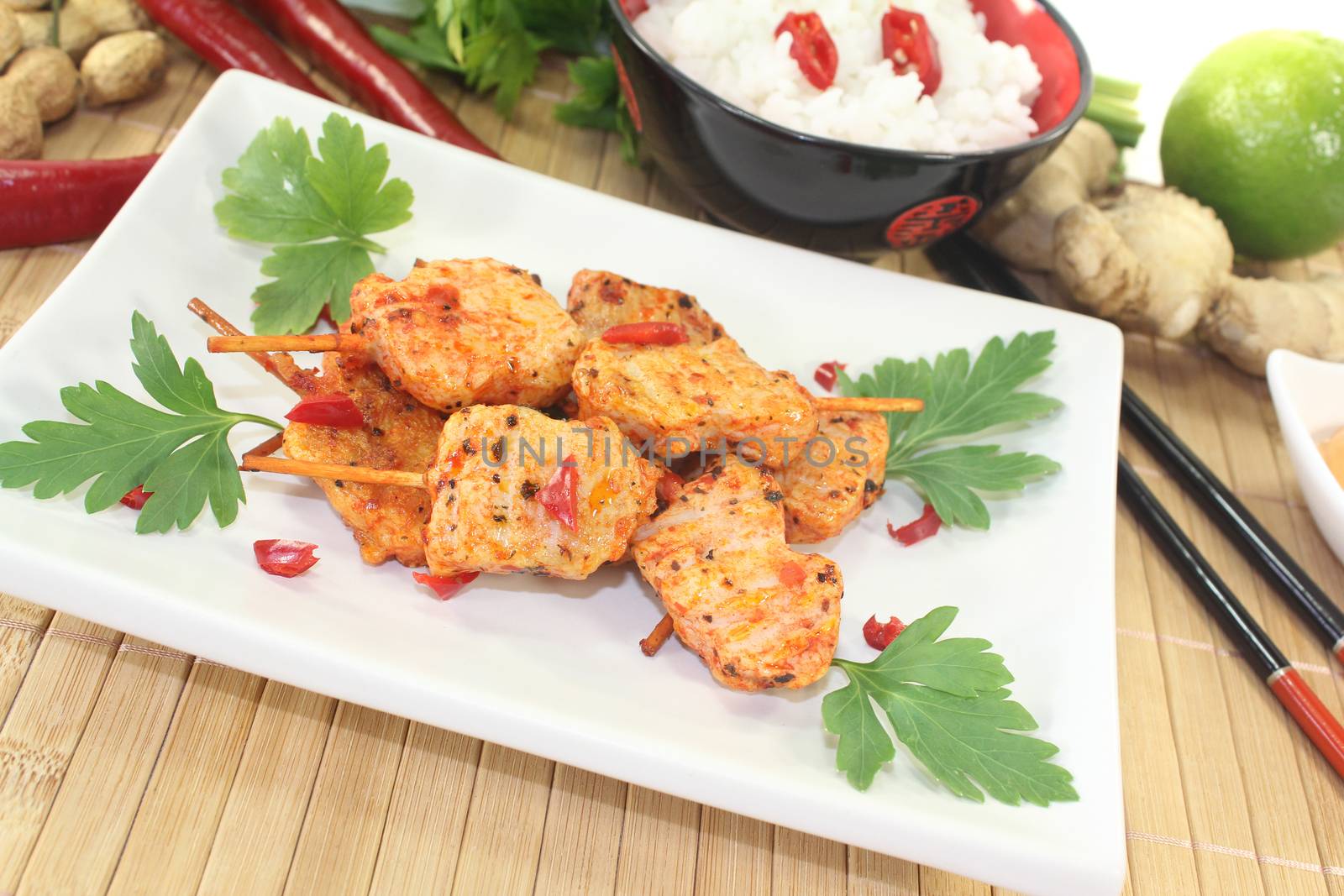 Asian satay skewers with rice and parsley on a light background