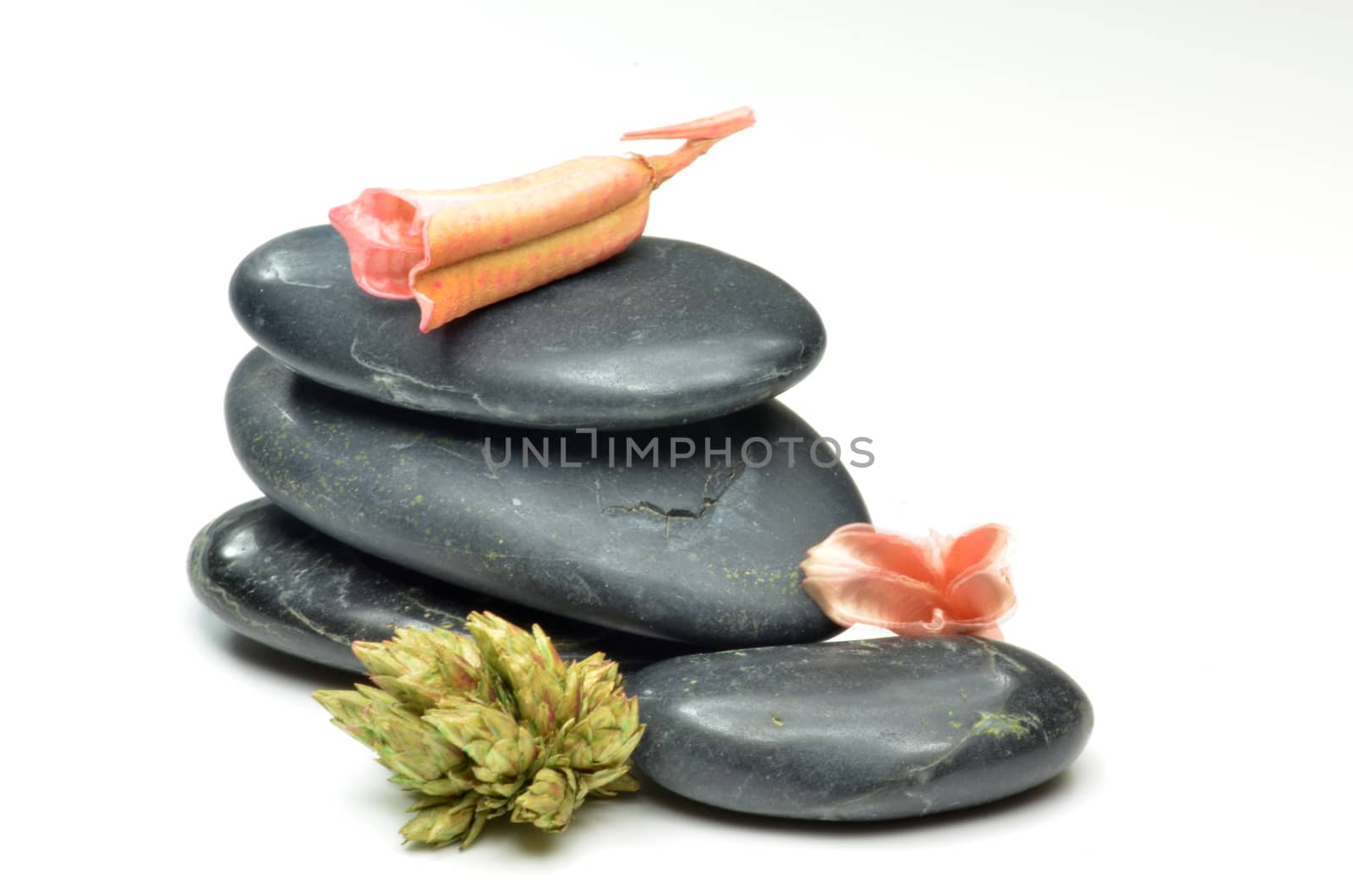 Concept of health. Stack of black stones with fake flowers