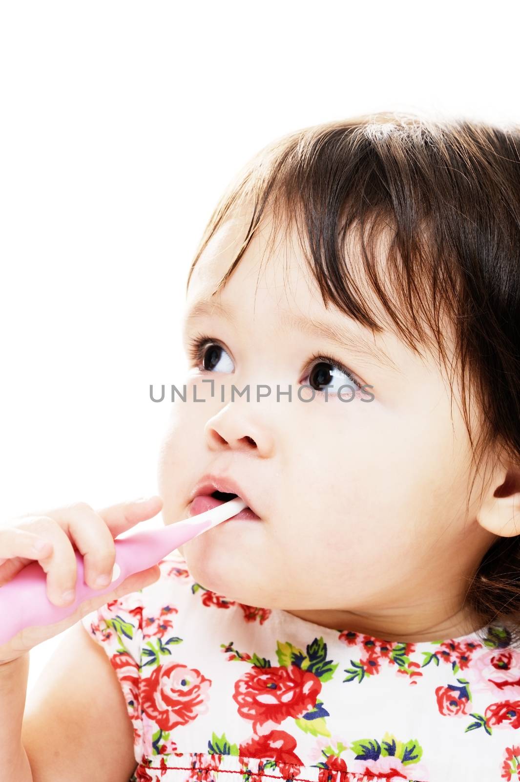 Little girl brushing her teeth with pink toothbrush