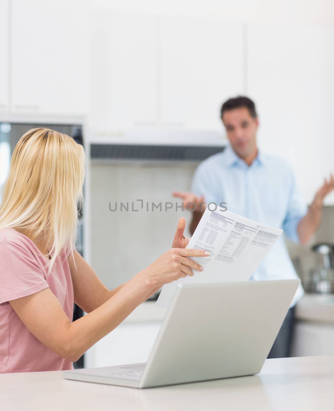 Woman and man with laptop and bill in the kitchen at home