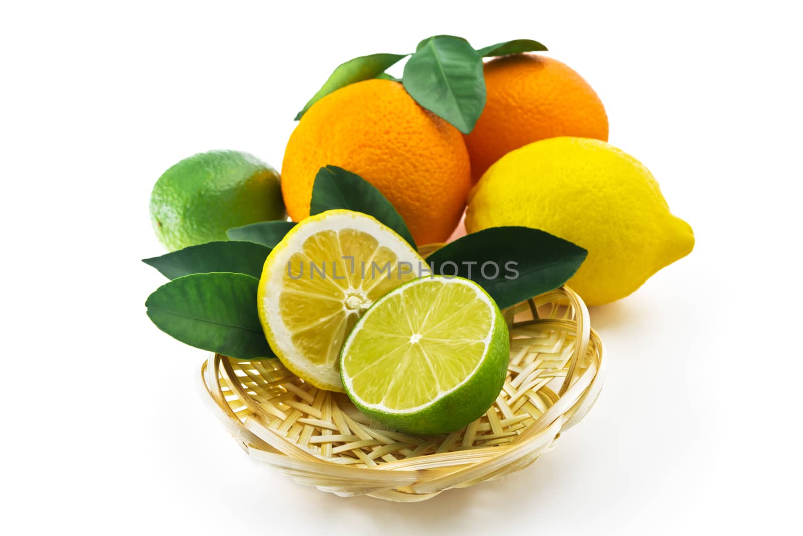 Orange, lemon, lime and half with leaves on a wicker saucer