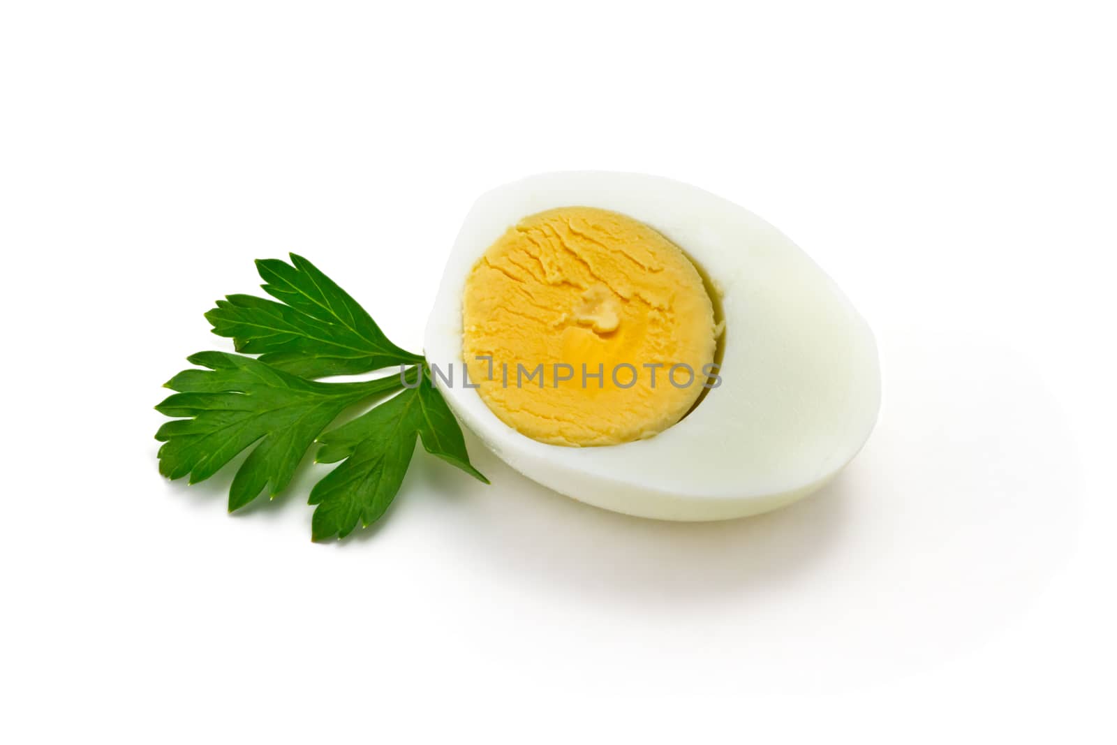 half of boiled egg with parsley leaves on a white background