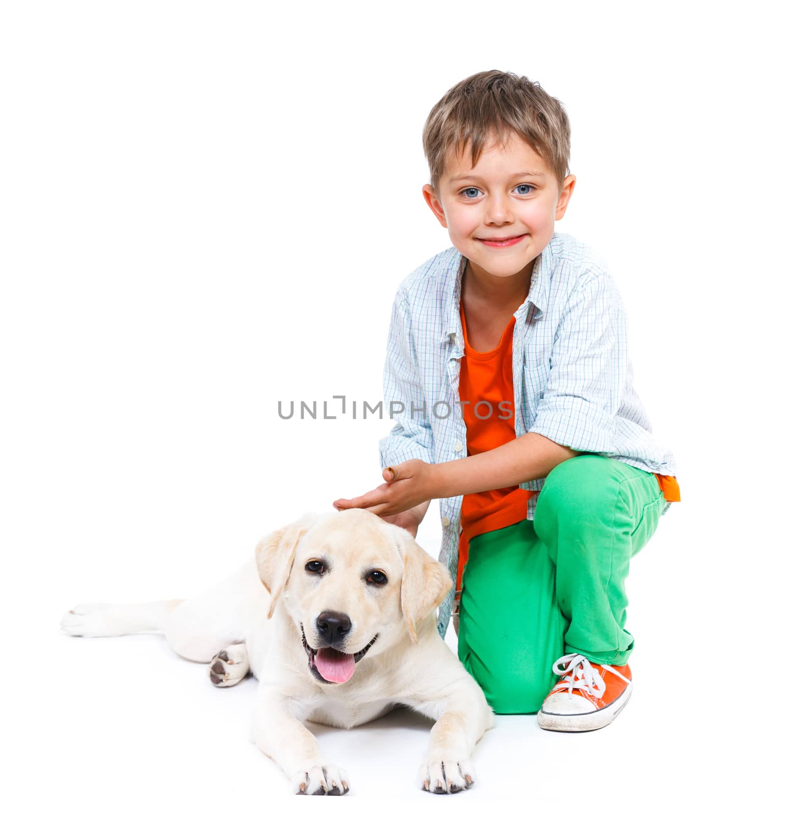 Cute little boy kneeling with his puppy labrador smiling at camera on white background