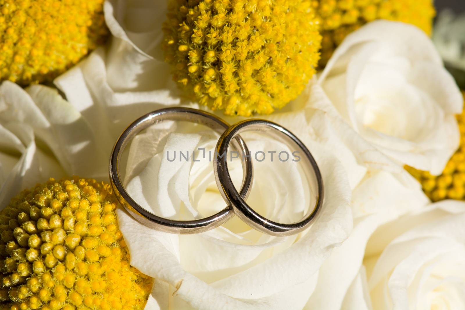 Details of wedding rings on a bridal bouquet in warm sun light