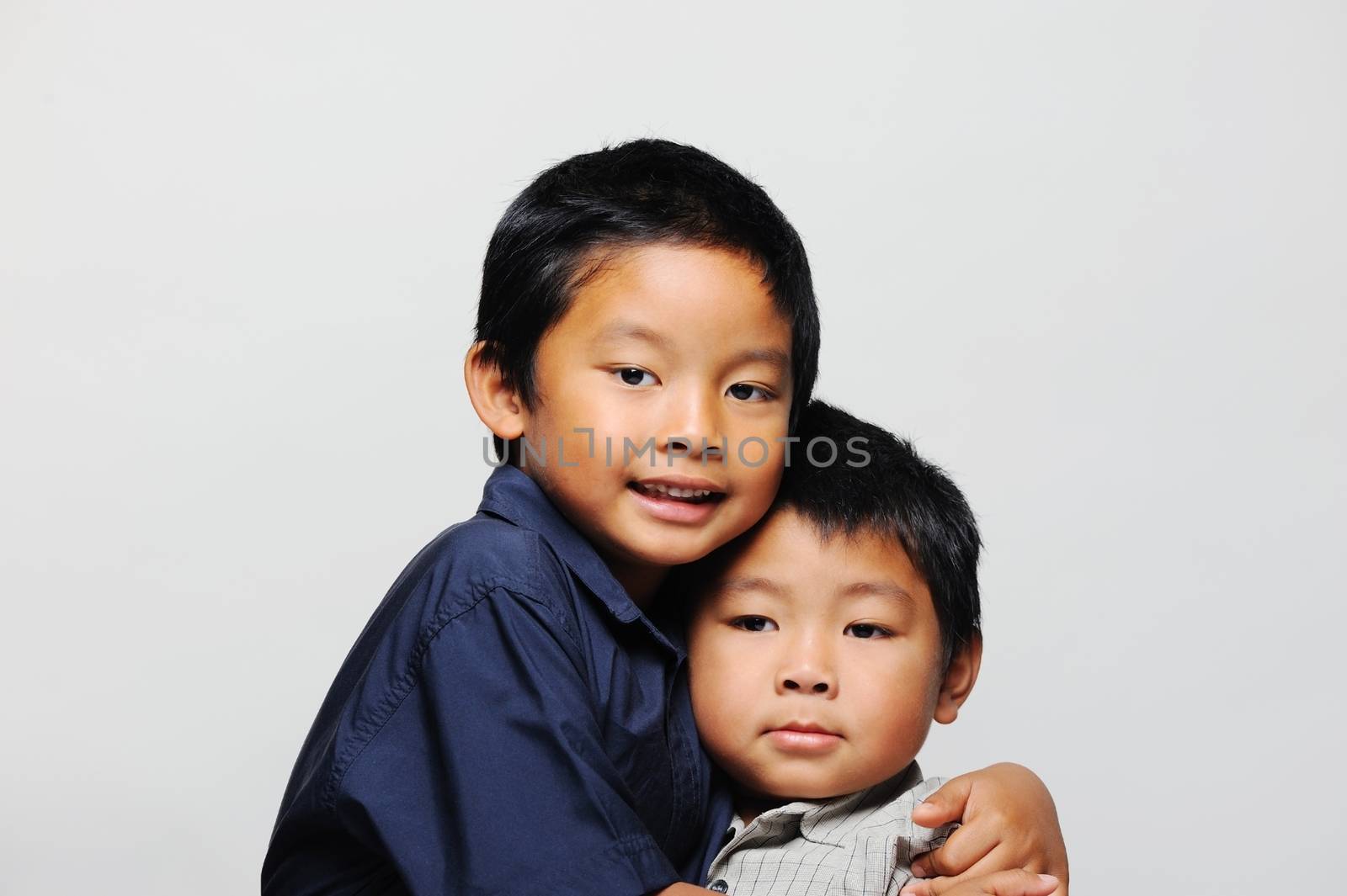 Cute asian brothers cuddle wearing smart shirts