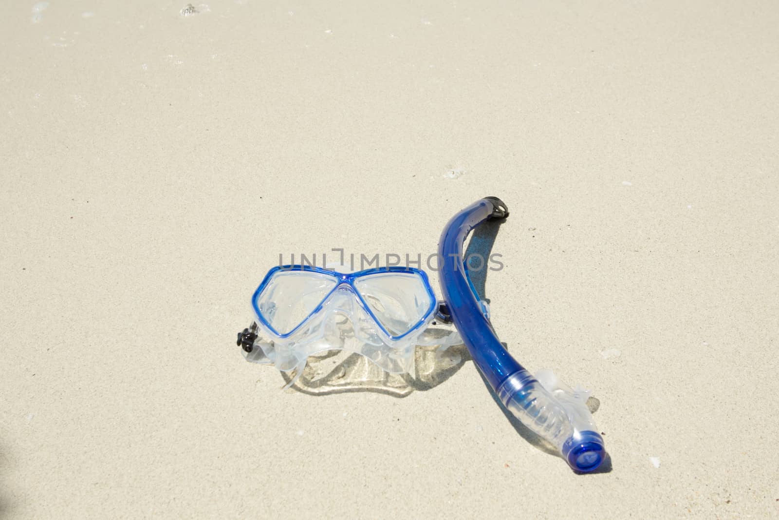 snorkel and mask on white sand  by wyoosumran