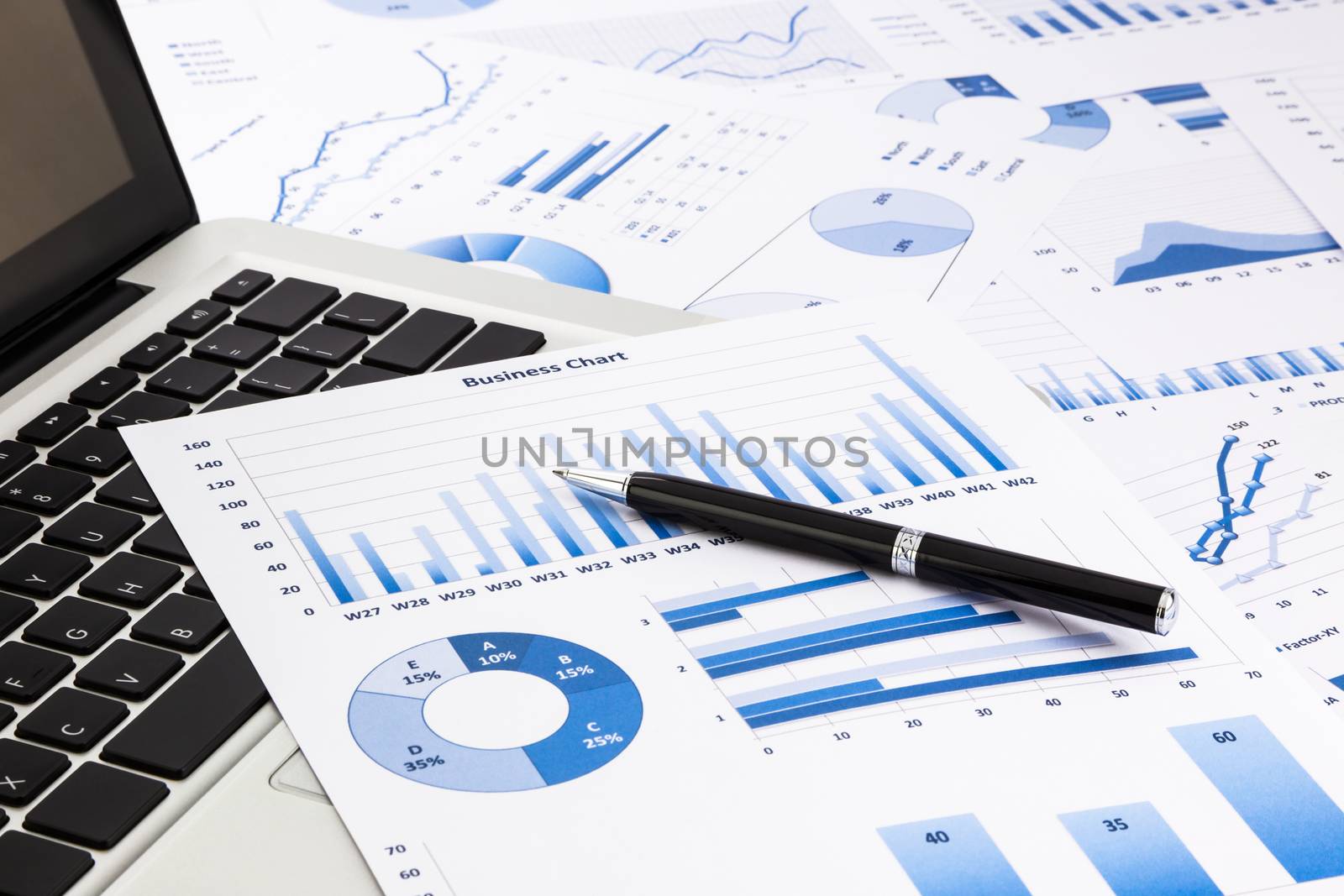 laptop and pen with blue business charts, graphs, statistic and documents background for education and business concepts