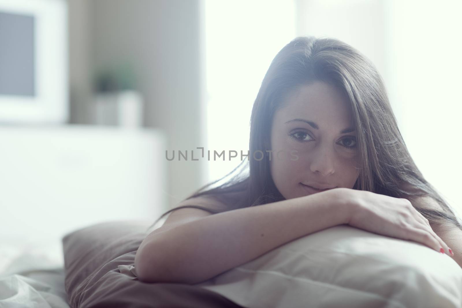 A gorgeous young woman while lying in bed 