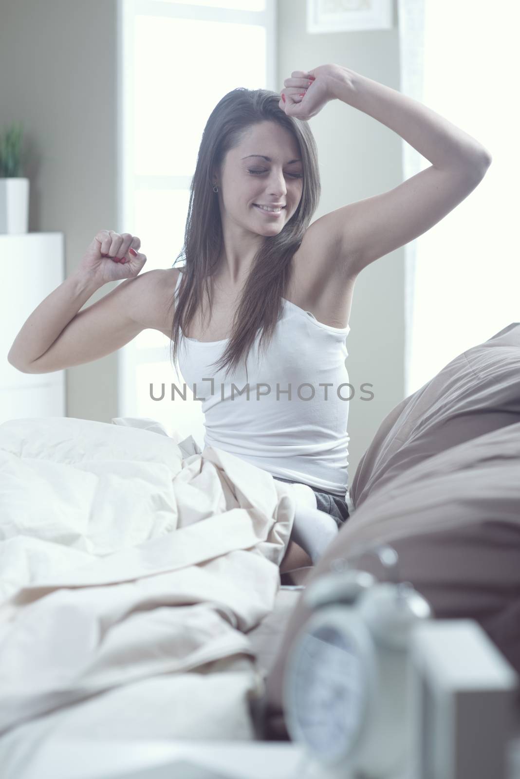 A smiling girl waking up and stretching her arms out 