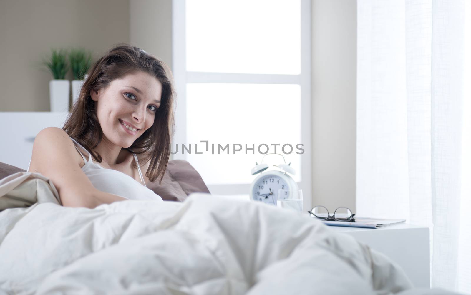 Young woman smiling while lying in bed 