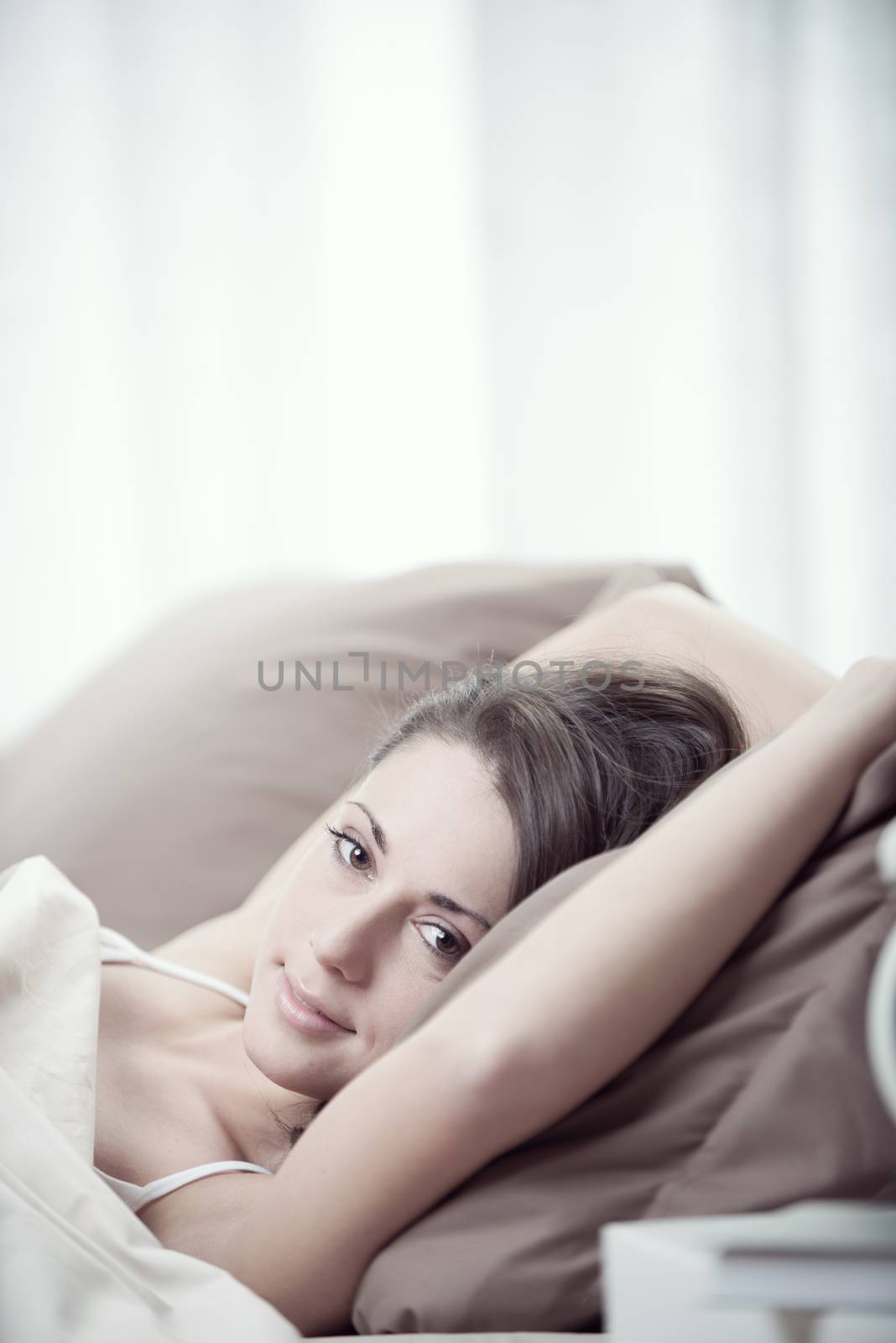 Young woman smiling while lying in bed 