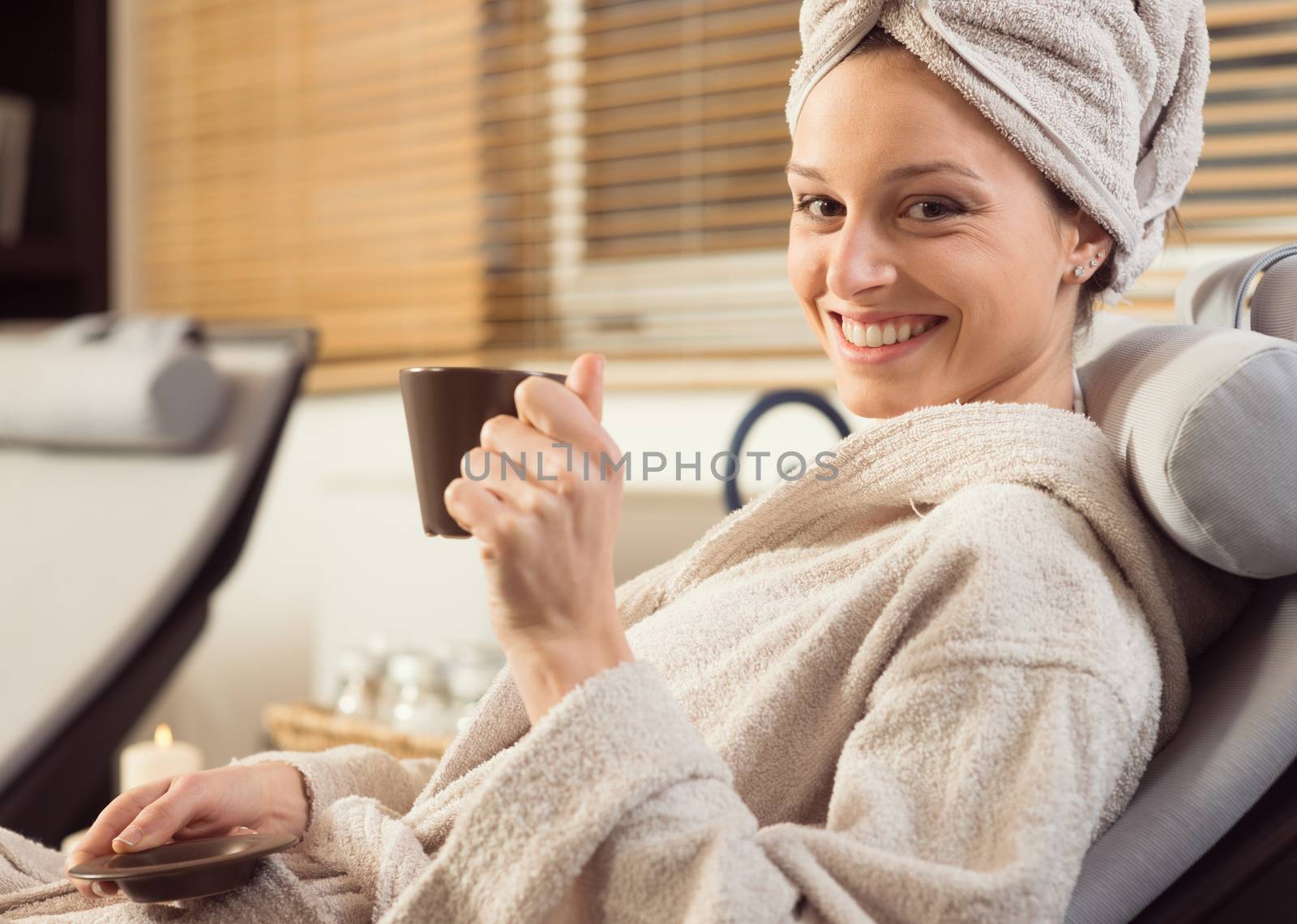 Young woman smiling and relaxing at spa, holding an hot healthy drink.