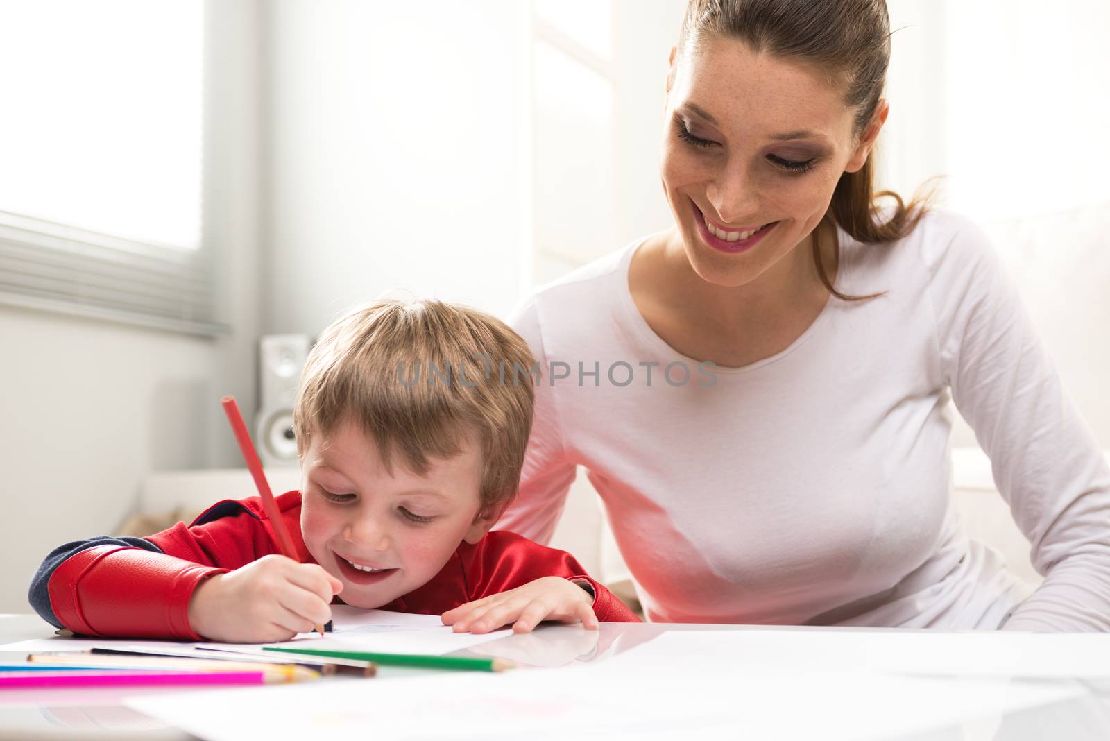 Mother and superhero child playing and drawing together in the living room.