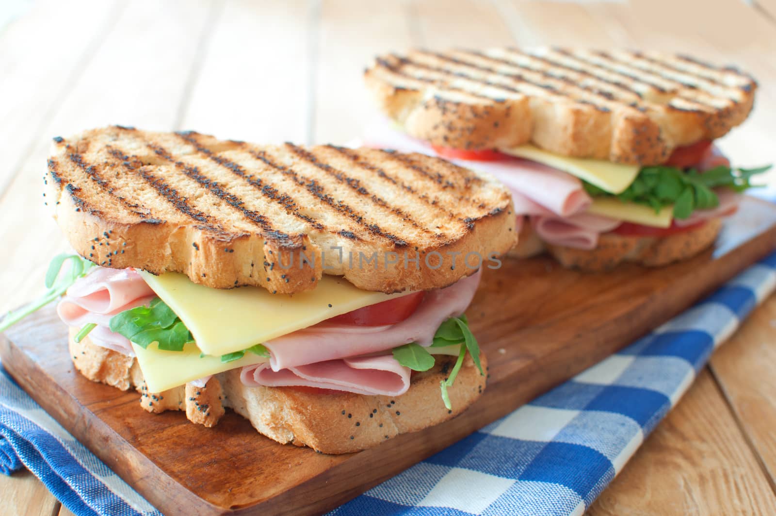 Grilled sandwiches with ham and cheese on top of a chopping board 