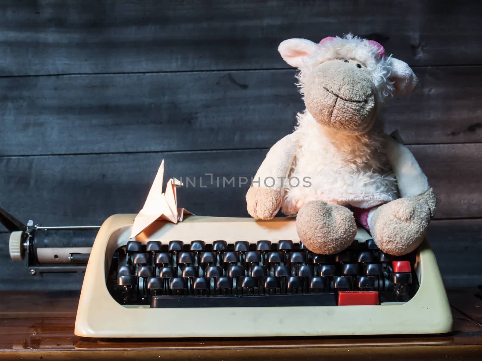 Typewriter with paper bird and Dolly the sheep on wood and wood background