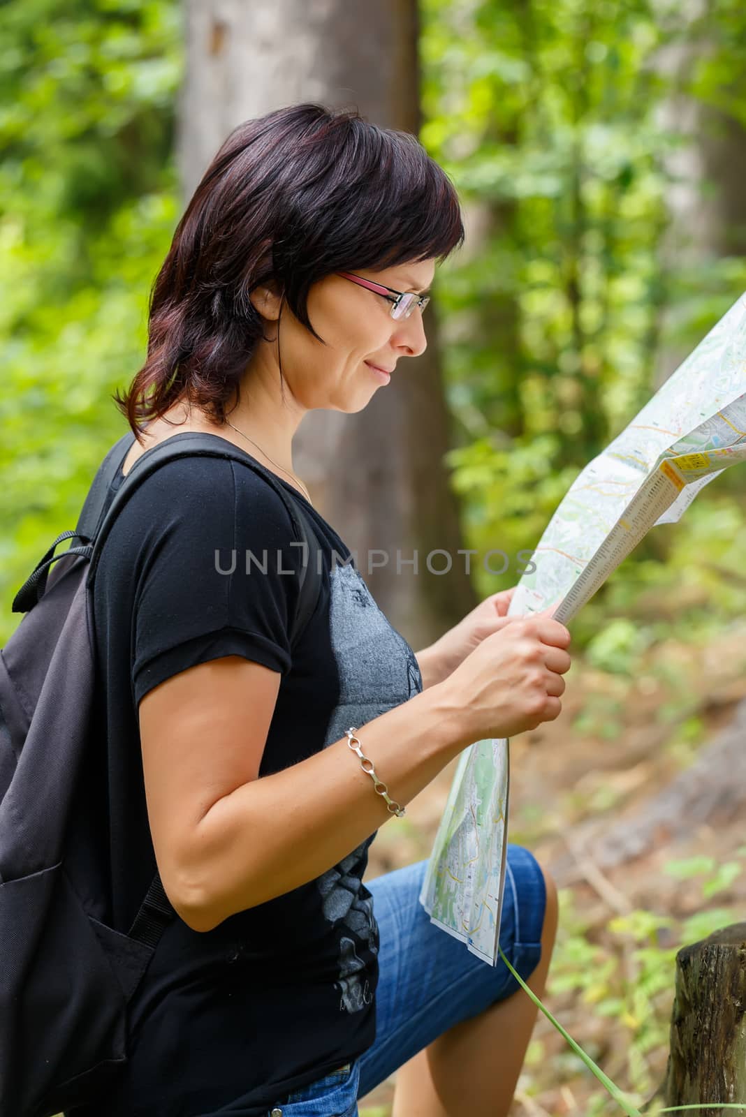 Woman sightseeing outdoors and holding a map in forrest