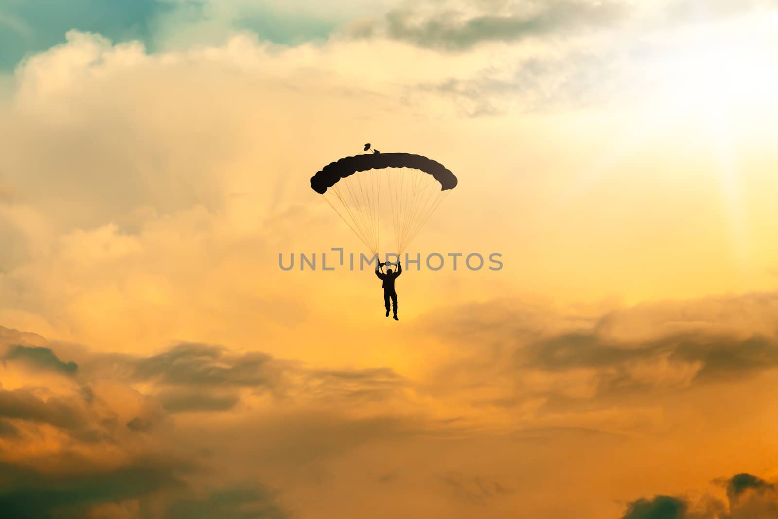 silhouette of unidentified skydiver parachutist on sky with sunset