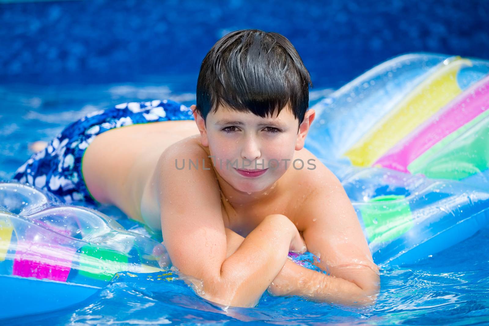 Happy young boy with inflatable water lounger in the swimming pool