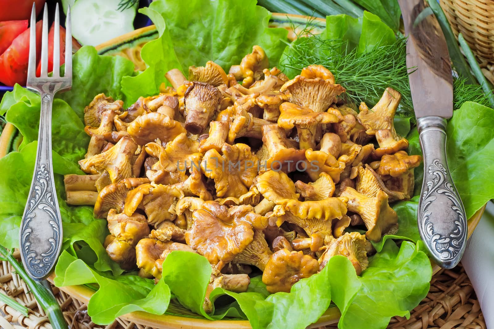 Dish with lettuce leaves on which appetizing fried chanterelles are located, are photographed by a close up