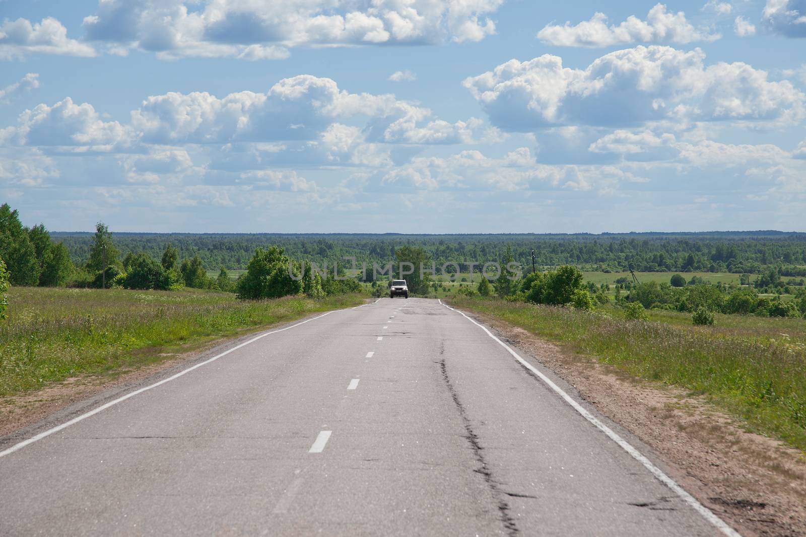 Summer lanscape with country road, trees and clouds 