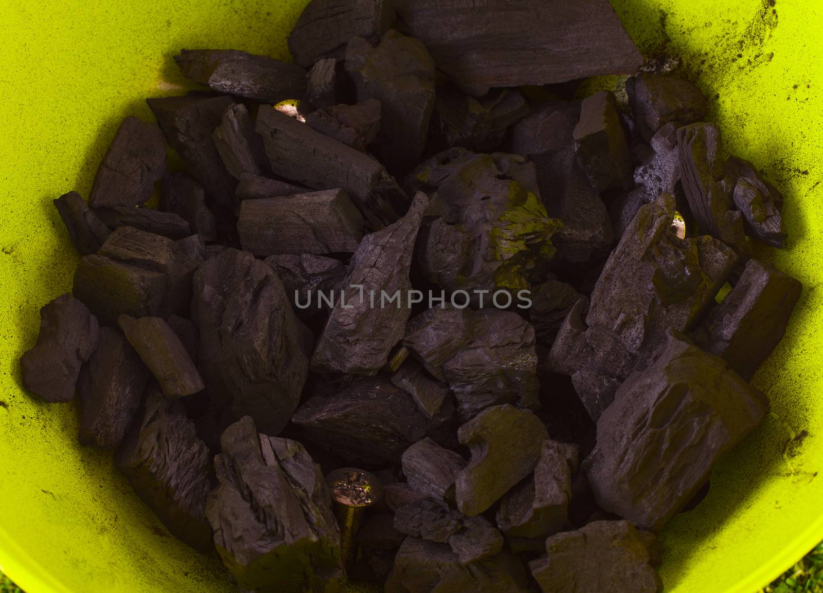 Pieces of black carbon over a green metal background
