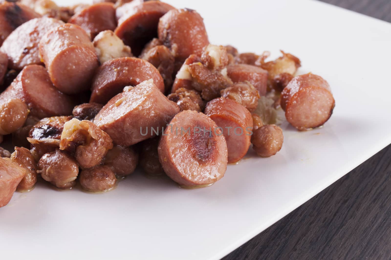 Wurstel and beans over a white plate