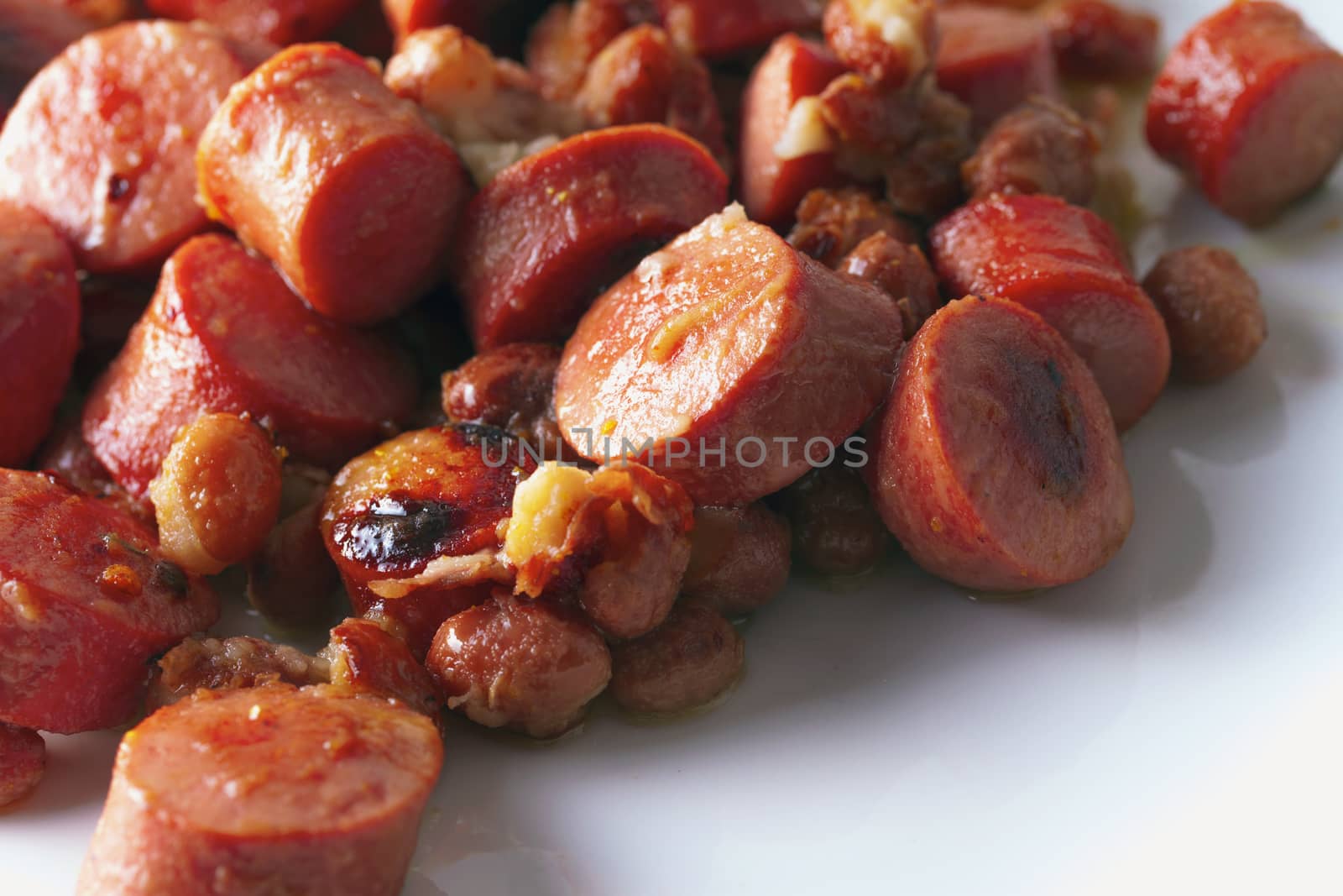 Wurstel and beans over a white plate