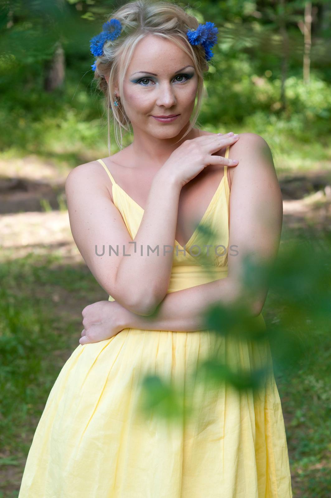 Pretty young girl in yellow dress in green forest