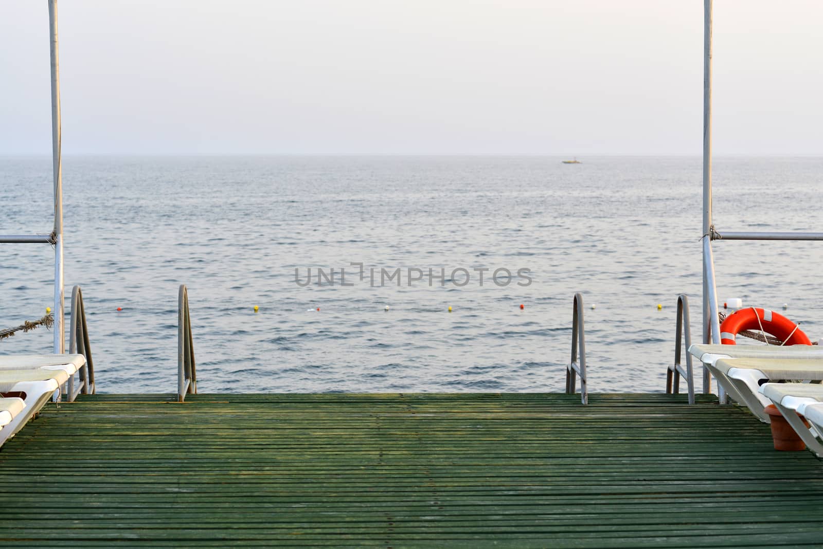 Wooden pier with metal handrails on the background of sea and sky